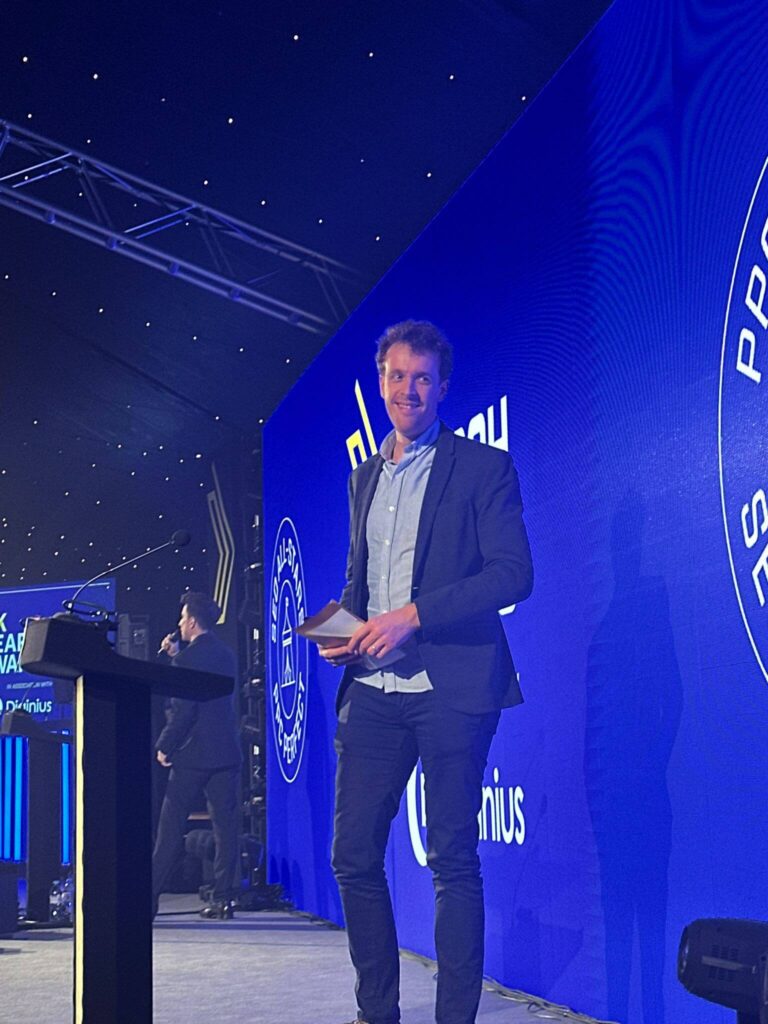 Owain Lloyd-Williams presenting on stage at search awards smiling